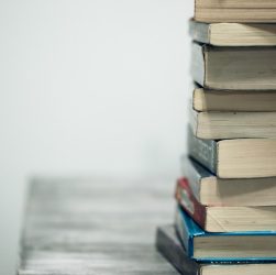 A stack of old books on a wooden table against a plain background