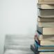 A stack of old books on a wooden table against a plain background