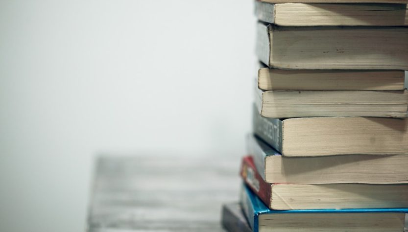 A stack of old books on a wooden table against a plain background