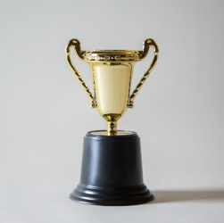 gold trophy on a black pedestal against a neutral background