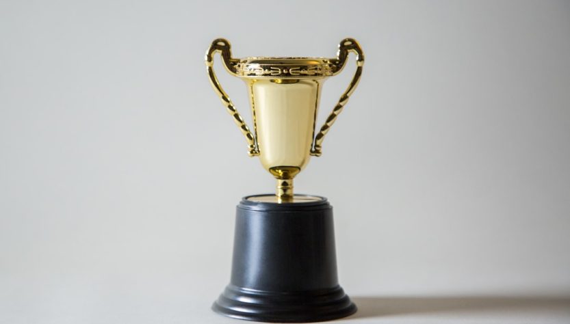gold trophy on a black pedestal against a neutral background