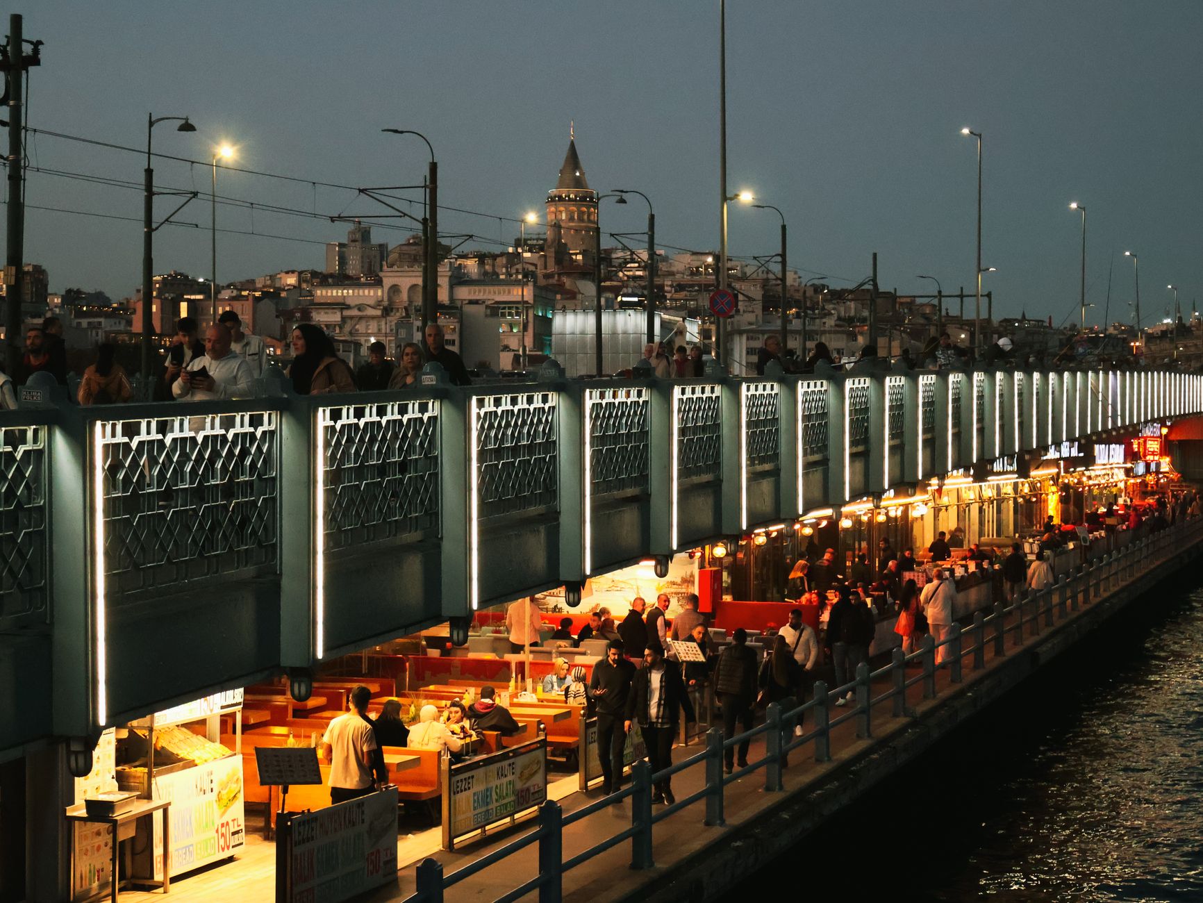 Night view of Galata Bridge bustling with people and distant Galata Tower in Istanbul. — Discover Why 82 Lottery Games Are Tr