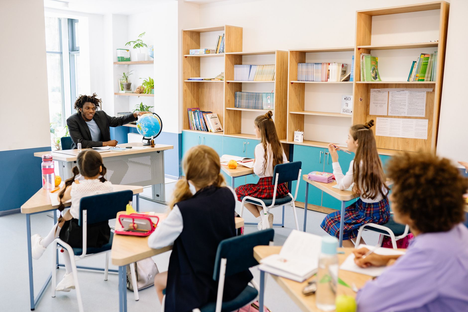 Teacher engaging students with a globe in a diverse classroom setting for interactive learning. — Kickstart Your Internationa